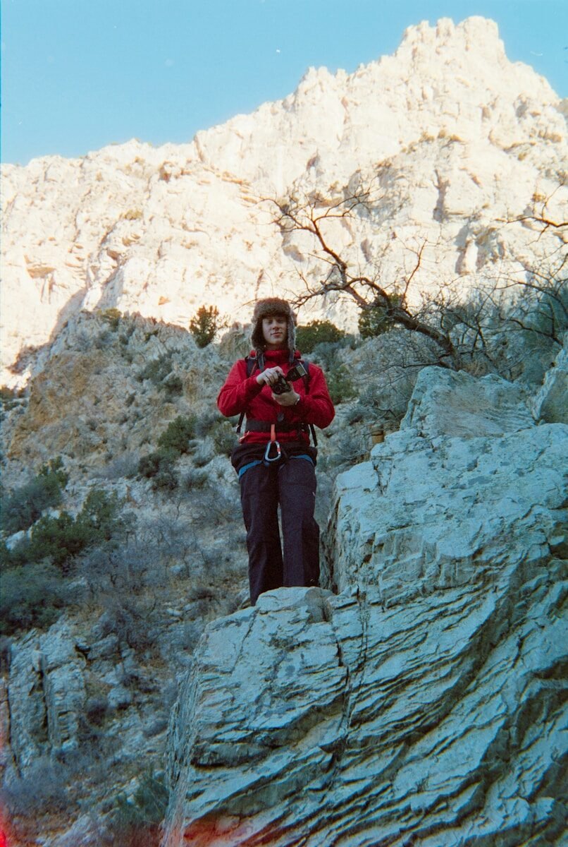 Woman in red jacket with climbing gear on rocks